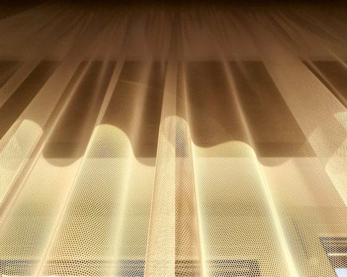 Sunlight softly filtered through sheer curtains over a desk