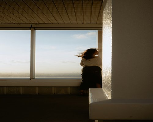 Person looking out a high-rise window away from their laptop
