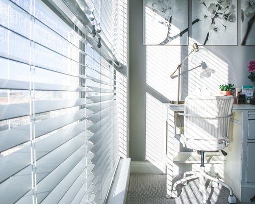 Sunlight streaming through window blinds into a home office